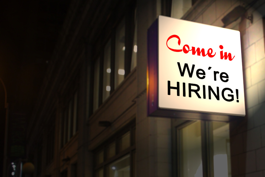 Ein beleuchtetes Schild mit dem Text "Come in - We're HIRING!"