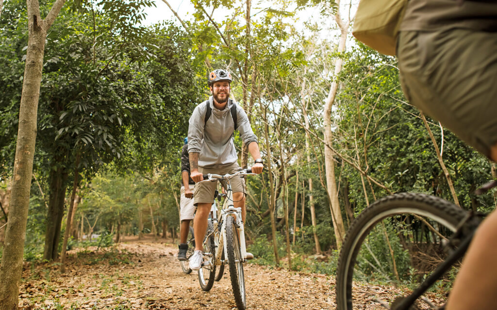 Junger Bursch macht mit seinen Freunden eine Biketour durch den Wald