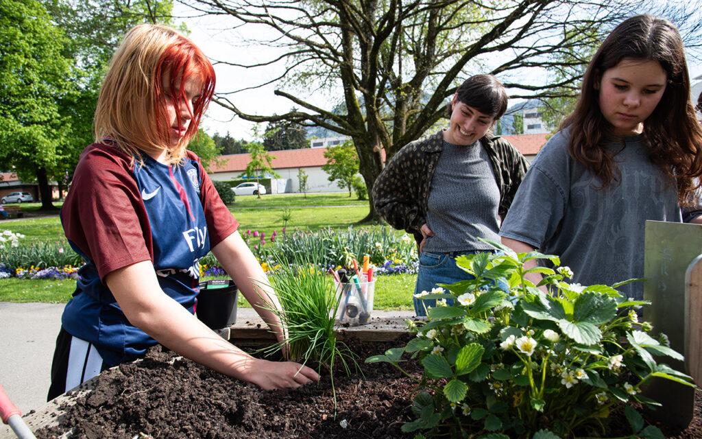 Zwei Jugendliche und eine Betreuerin bei Gartenarbeiten.