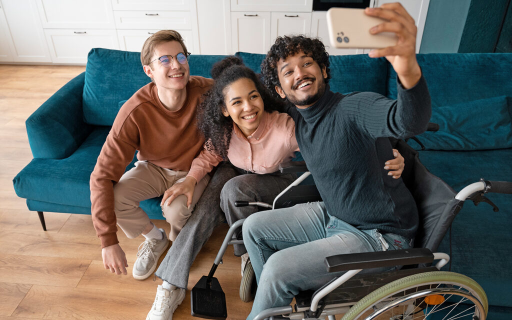 Jugendlicher im Rollstuhl macht mit seinen Freunden ein Selfie