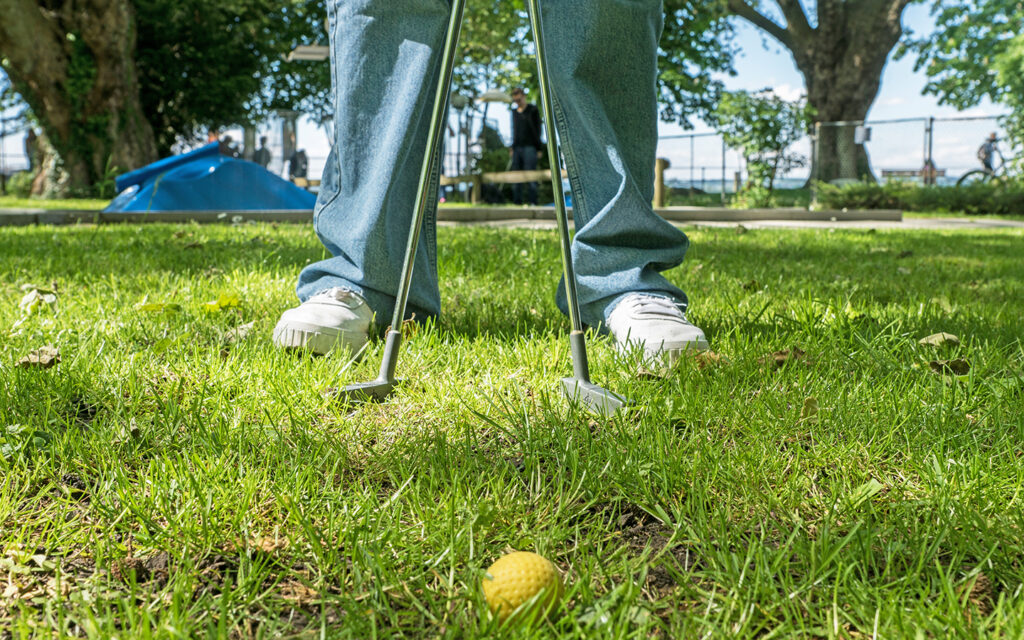 Jugendliche steht auf dem Minigolfplatz - man sieht nur ihre F&uuml;&szlig;e und den Minigolfball dazwischen