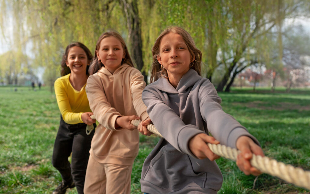Jungendliche spielen Seilziehen und eine Gruppe Mädchen zieht am Seil