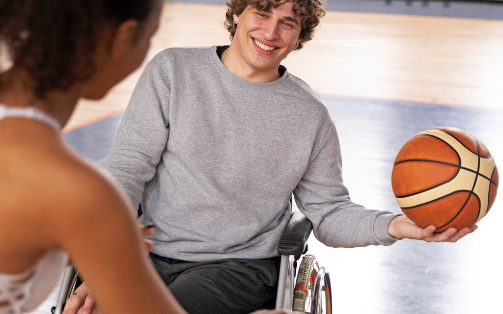 Junger Mann in einem Rollstuhl spielt Basketball
