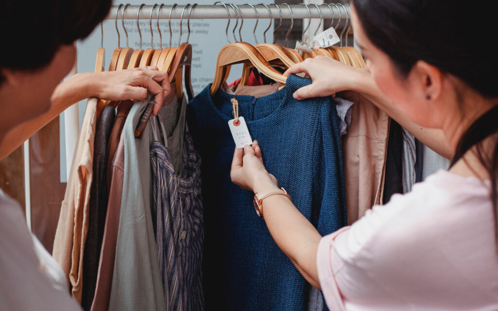 Zwei Frauen schauen ein Preisschild von einem Kleidungsst&uuml;ck an.