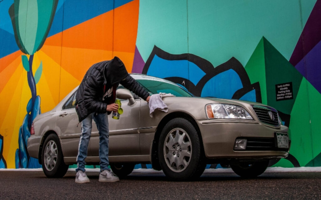 Ein junger Mann putzt sein Auto.