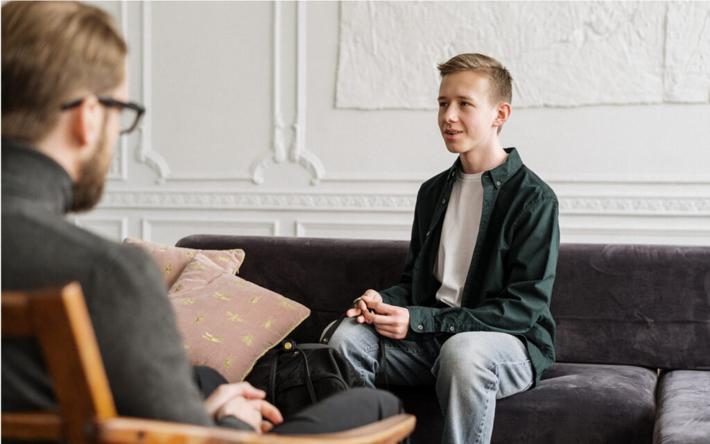 Jugendlicher sitzt in einer Therapiesitzung.