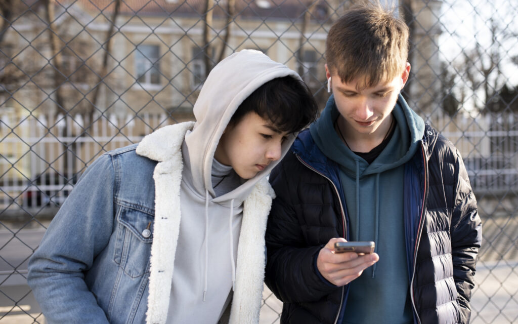 Zwei Burschen schauen in ein Smartphone
