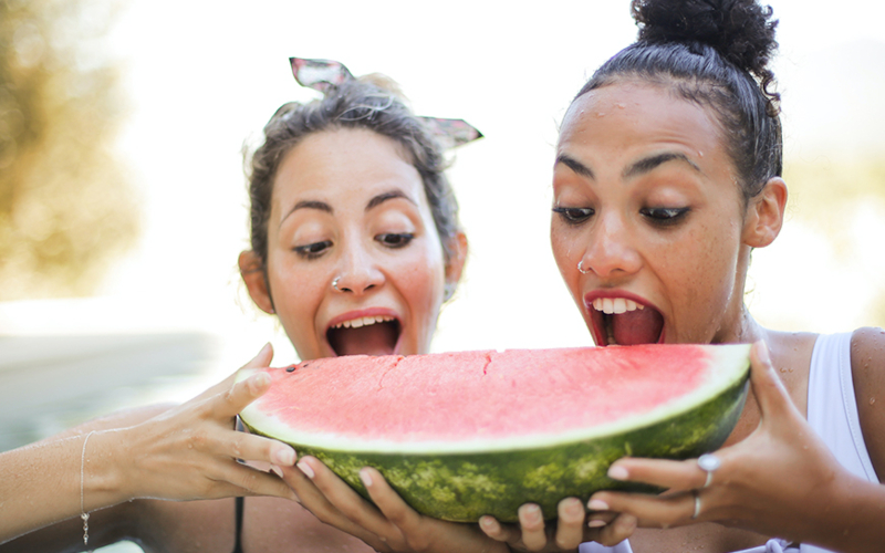 Zwei Jugendliche bei&szlig;en in eine Wassermelone