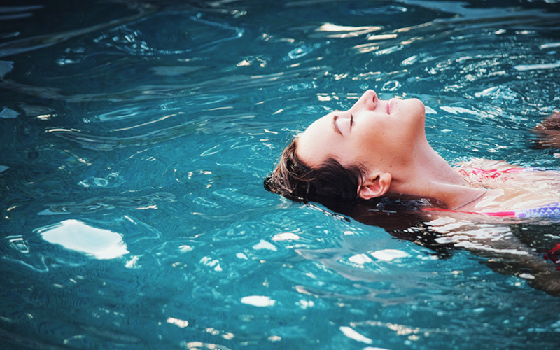 Eine junge Frau liegt im einem Pool.
